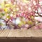 Empty wooden deck table over blooming tree bokeh background for product montage display.