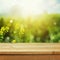 Empty wooden deck table over green meadow bokeh background for product montage display. Spring or summer season