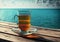 Empty wooden deck table over ocean background with glass cup of tea and saucer on wooden table, a pleasant relaxing hot drink