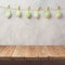 Empty wooden deck table over rustic wall background with eggs decoration garland. Easter holiday