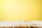 Empty wooden deck table over yellow wallpaper background.