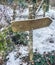 Empty wooden direction sign post with no text on it covered in a layer of snow during a snow storm in Christmas winter time