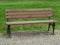 empty wooden iron bench on the park - grass and pavement background