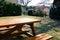 Empty wooden picnic table with benches in backyard on sunny day