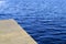 Empty wooden pier and blue water surface with small waves. High angle view to lake, sea or river. Water texture.