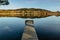 Empty wooden pier on lake. Spring pond village in background. Sunny calm idyllic weather. Serenity scenery.Meditation without