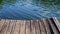 Empty wooden pier with ripple water. Lake water surface, summer day in the park