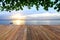 Empty wooden pier on sea coast and green leaves over head on tropical beach