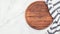 Empty wooden pizza platter with napkin set up on marble stone kitchen table. Pizza board and tablecloth on white marble background