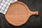 Empty wooden pizza platter set up on dark concrete. Pizza tray on dark concrete background flat lay and copy space