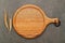 Empty wooden pizza platter with wheat ears  set up on dark concrete background