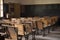 empty wooden row lecture chairs in a classroom with the blackboard on the wall and students' books on their desks