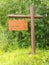 Empty wooden sign board dense green forest edge