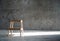 Empty wooden stepladder chair over concrete wall background