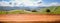 Empty wooden table with blurred panoramic background of summer landscape with road and mountain village for display or montage