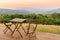 Empty wooden table and chairs on terrace. Beautiful seating with landscape mountains view while sunset