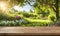 An empty wooden table in the foreground, with a blurred country house in the background against a verdant garden setting