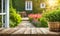 An empty wooden table in the foreground, with a blurred country house in the background against a verdant garden setting