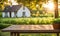 An empty wooden table in the foreground, with a blurred country house in the background against a verdant garden setting