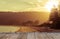 Empty wooden table in front of calm sunny beach with sunset in background