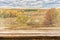 Empty wooden table with picturesque autumn landscape of view from the hill to the lowland with forest and swamps. Mock up for