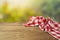 Empty wooden table with red checked tablecloth over green bokeh background. Spring and easter mock up for design