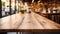 Empty wooden table surface closeup, blur cafe bar restaurant or retail shop interior background, bokeh lights