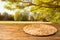 Empty wooden table with wicker round placemat over autumn nature park background