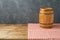 Empty wooden table with wine barrel and tablecloth over black wall background