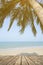 Empty wooden terrace over tropical island beach with coconut palm