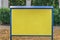Empty yellow information board with blue frame in city park