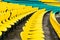 Empty yellow plastic chairs in symmetrical rows in a cricket stadium