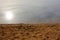 Empty yellow sandy beach, dark river water, and sun reflection. Nostalgic summer landscape.