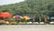 Empty yellow sun loungers under multi-colored beach umbrellas on the wind on the yellow sand against the background of a green mou