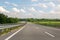 Almost emty asphalt highway with blue cloudys sky on background. Toll roads construction