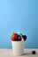 Enamel Bucket Filled with Fresh Fruit Berries on Wood with Blue