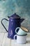 Enameled blue tea pot and mugs on table