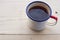 Enameled camping mug with string tea on a wooden texture.