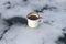 Enameled camping mug of the traveler with hot lavender tea and tea bag on the beautiful scenic ice in the form of a cloud.