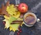 An enameled cup of hot tea, autumn leaves, a rebright autumn portrait of a cute smiling little girl