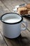 Enameled cup of milk on a wooden table