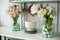 Enameled white colander, plates, bouquet of flowers in vase and Easter eggs on kitchen table. Front view of countertop with kitche