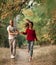 Enamored couple holds hands and runs on forest path.