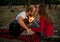 Enamored couple sits on picnic in forest with guitar on background of bonfire flame.