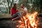 Enamored couple sits and smiles on picnic in forest on bonfire f