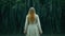 Enchanted Wanderer: Girl in Long White Dress Strolls Through the Dark Forest