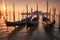 Enchanting beauty of a sunset in Venice, Italy. Gondolas gracefully parked along the serene shore, their reflections shimmering on