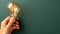 Enchanting dark green background with hand holding light bulb and ample empty space for text