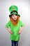 Enchanting smiling small girl with decorative red beard in leprechaun\\\'s hat with gold clover leaf. Saint Patricks Day