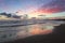 Enchanting sunset. Storm sea with high waves. Unbelievable blue, pink, orange colors of the sky are reflected on the wet sand.